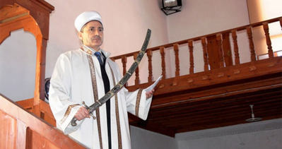 O camide imam hutbeyi kılıçla okuyor