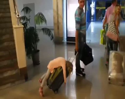 Uyuyakalan kızını bavulun üzerinde taşıdı